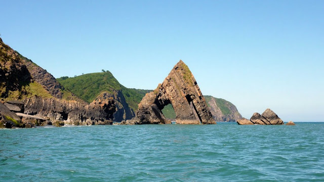 A picture of Black Church Rock, juting up ike a sharks fin and with and arch through the middle